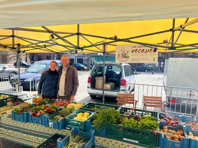 Madeleine et Luc au marché derriere les bacs de fruits et légumes bio